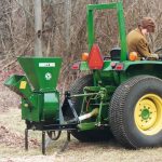 A woman using a Mighty Mac Hammermill Shredder Chipper TPH123 hitched to a tractor
