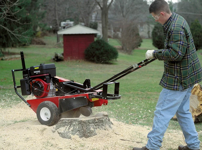 man using a stump cutter to remove the tree stump